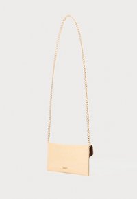 Beige keinonahkaista käsilaukkua, jossa on krokotiiliraidoitus, ohuella kultaketjuhihnalla ja suorakaiteen muotoisella rakenteella. Minimalistinen muotoilu.
