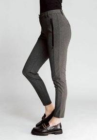 Slim-fit grey pants with textured fabric, side zipper detail, and contrasting black accents. Paired with chunky black shoes.