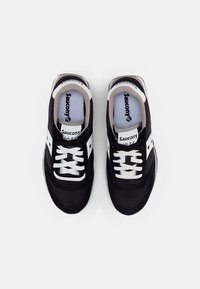 Černé a šedé tenisky s vrškem z semišové a síťované látky, s bílými tkaničkami, akcenty loga a polstrovaným límcem pro pohodlí.