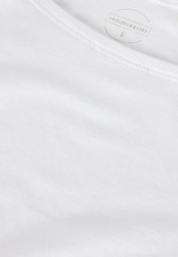 Hvid bomulds-t-shirt med v-hals, glat tekstur og delikat syning. Etiketten indeni viser "intimissimi" og størrelse "S."