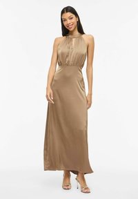 Robe longue sans manches en satin de couleur marron clair unie, avec un corsage froncé et un col licou. Texture lisse, design longueur au sol.
