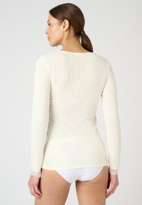 Top de manga larga, canalé en tejido crema claro con detalles de encaje en los puños; corte recto y ajuste slim, con escote redondo.