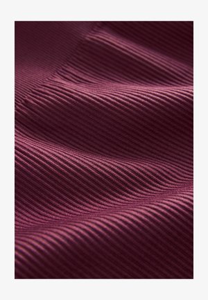 Textilie s jemně drážkovanou strukturou v hluboce burgundské barvě, která vykazuje záhyby vytvářející vlnkový vzor na povrchu.