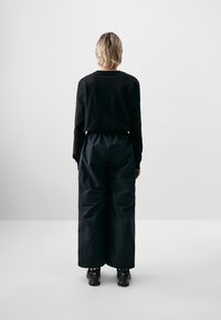 Zwarte lange mouwen shirt en losse zwarte broek met een elastische tailleband, met een gladde textuur en een recht gesneden ontwerp.