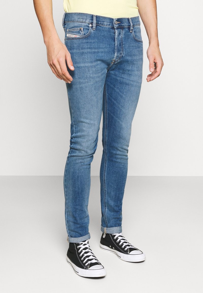 Ljusblå denim jeans med slim fit, femficksdesign och subtila slitningar. Uppvikta fållar i kombination med svarta sneakers.