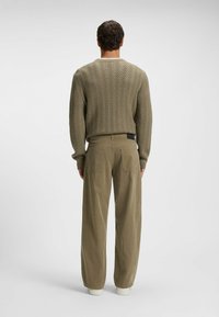 Maglione a maglia verde oliva con un motivo a zigzag texturizzato, abbinato a pantaloni cargo verde oliva chiaro con due tasche posteriori e un fit rilassato.
