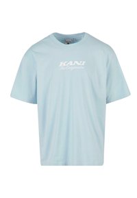 Gaiši zilas īsām piedurknēm t-krekls, kas izgatavots no kokvilnas. Tam ir apaļš kakls un balta drukāta teksta uzraksts "KANI The Originator" uz krūšu.