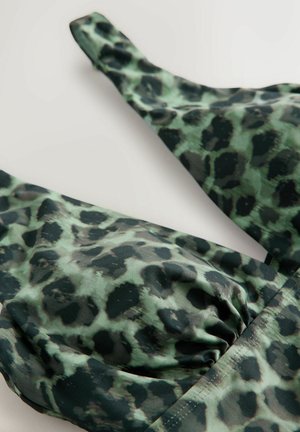 Närbild av grön och svart leopardmönstrad tyg med rynkad söm på plaggets band och kupor.