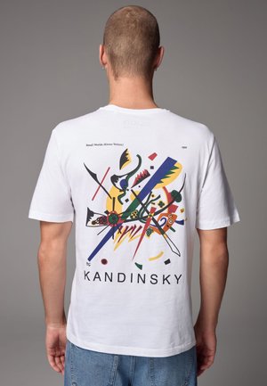 Biała bawełniana koszulka z kolorową abstrakcyjną grafiką na plecach, z napisem "KANDINSKY" i "Małe Światy (Kleine Welten)" poniżej.