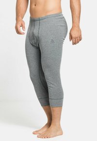 Graue, enganliegende Leggings aus einem weichen Baumwollgemisch. Sie haben eine Länge bis zur Mitte der Waden, einen elastischen Bund und ein dezentes Logo auf der Vorderseite.