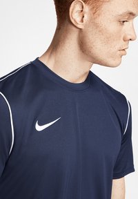 Maglietta sportiva navy con dettagli bianchi e logo Nike. Realizzata in tessuto morbido, presenta un colletto rotondo e maniche corte.