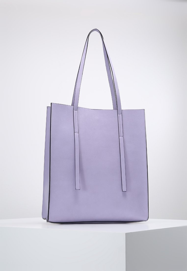 Sac fourre-tout en cuir lavande avec de longues poignées plates, une forme rectangulaire, une texture lisse et un design minimaliste. Présente des bords contrastants.