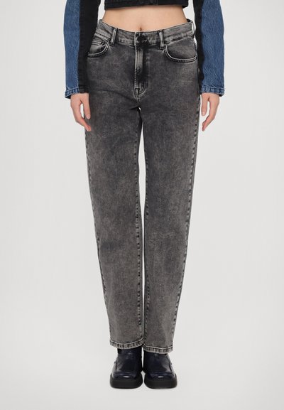 Jeans de tiro alto y pierna recta en denim negro desgastado. Cuenta con cinco bolsillos, costuras sutiles y un cierre de botón clásico.