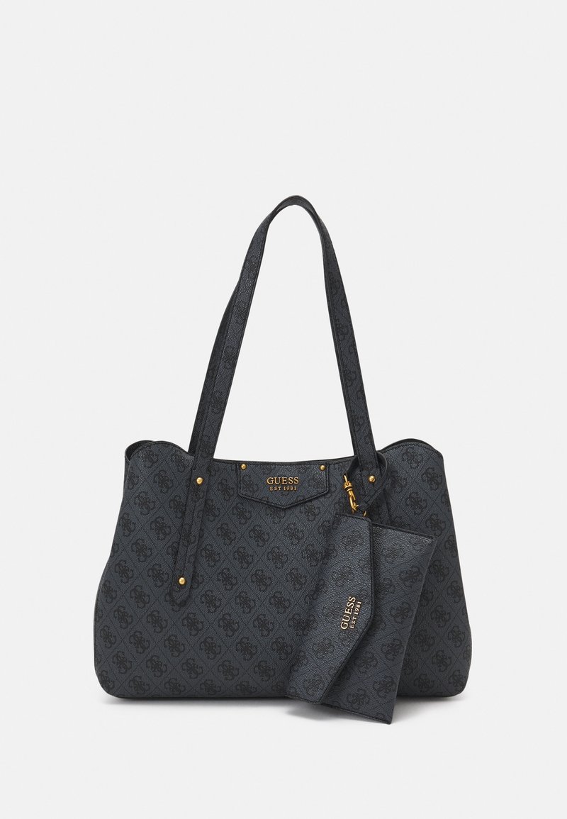 Sac à main Guess noir à motif avec pochette amovible assortie, logo doré et deux bandoulières sur fond blanc.