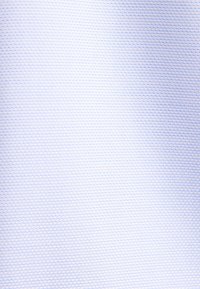 Gros plan d’un tissu blanc texturé avec un motif carré diagonal subtil sur la surface.