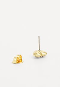 Gold-toned earrings featuring a heart-shaped design with a smooth finish and a crystal-embellished bottom section. Includes a stud backing.