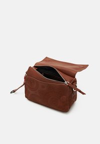 Borsa in pelle marrone con motivi floreali in rilievo, chiusura con zip e tracolla staccabile. Presenta una texture simile al camoscio e un design minimalista.