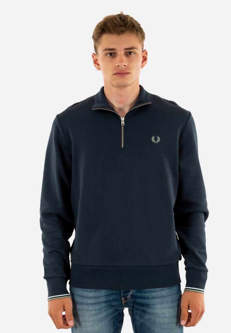 Sudadera tipo quarter-zip en color azul marino, hecha de una tela suave, con un pequeño logo bordado en el pecho y puños acanalados con un acento a rayas.