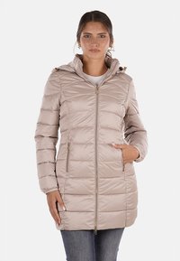 Giacca imbottita beige con chiusura a zip frontale, due tasche laterali e cappuccio. Presenta un design trapuntato e dettagli in metallo dorato.