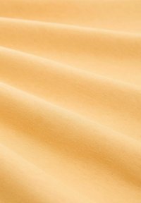 Baumwollstoff in sanftem Gelb, mit glatter Textur, sanften Falten und subtiler Glanz, der ein warmes, harmonisches Erscheinungsbild schafft.