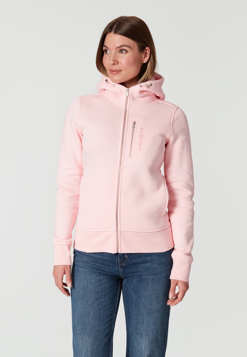 Sudadera rosa claro con cremallera completa, bolsillos tipo canguro y capucha con cordón. Cuenta con puños y dobladillo acanalados, hecha de una tela suave y texturizada.