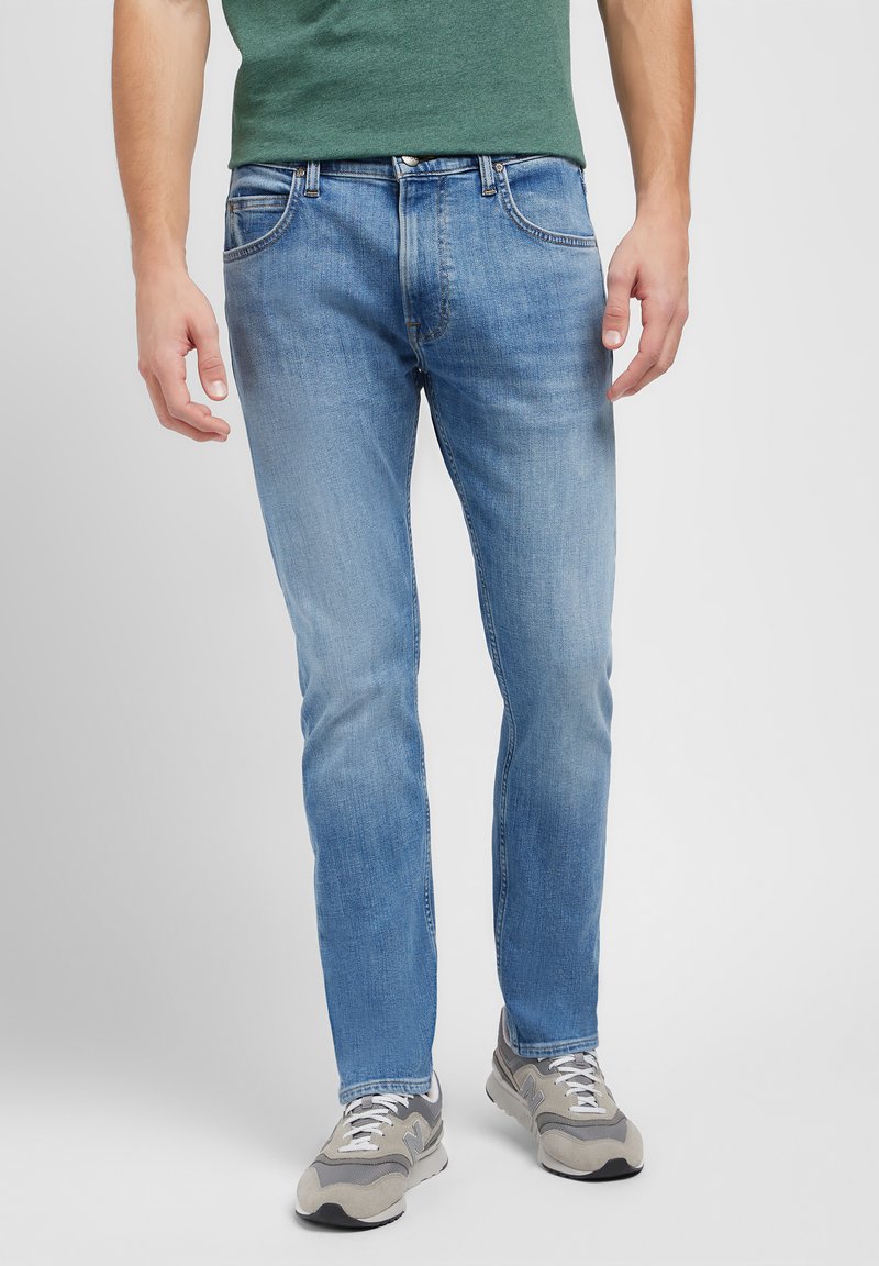 Lyseblå denim jeans med rett ben, med fem lommer, kontrastsøm og en falmet finish. Kombinert med grå joggesko.