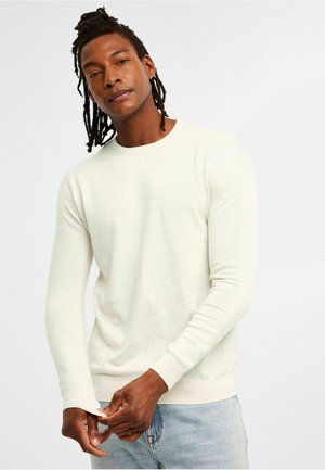 Ljusbeige långärmad tröja gjord av ett mjukt material, med en rund hals, ribbade ärmslut och en figurnära siluett.