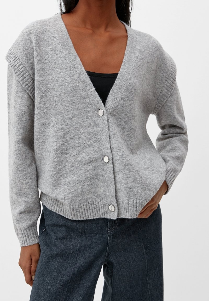 Grå stickad kofta med V-ringning, ribbade detaljer vid axlar och ärmslut samt fem runda silverknappar längs fram.