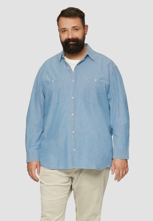 Lichtblauwe button-up shirt van denim materiaal, met twee borstzakken, lange mouwen en een ontspannen pasvorm. Draag het over een wit T-shirt.
