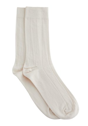 Paire de chaussettes simples côtelées blanc cassé avec bords, présentées à plat et superposées sur un fond blanc.