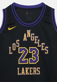 Czarny koszulkowy strój do koszykówki z fioletowo-żółtymi akcentami. Na przodzie wyraźnie widnieje napis "LOS ANGELES" oraz numer "23", a także logo Nike.