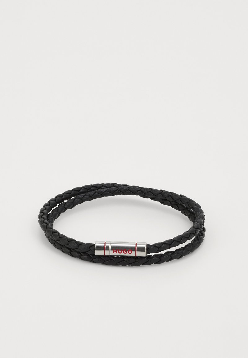 Svart flätad läderarmband med en silverlåsning som har ordet "HUGO" med röda accenter. Dubbelslingdesignen förbättrar textur och stil.
