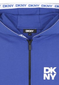 Sweat à zip bleu avec une fermeture éclair noire, un logo blanc et un col contrasté. Fabriqué en tissu doux, idéal pour une tenue décontractée. Étiquette de taille visible.