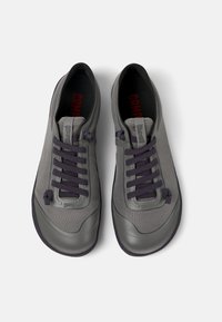 Szare sneakersy z siateczkową cholewką i gumową podeszwą, z ciemnofioletowymi sznurowadłami i akcentami. Lekka konstrukcja z okrągłym czubkiem.