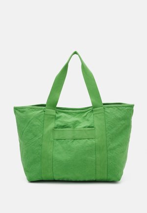 Large green canvas tote bag with two long handles and a front pocket, shown on a plain white background.