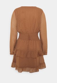 Robe marron transparente à manches longues avec une taille smockée, un ourlet à volants superposés et une texture parsemée de points sur toute la surface. Vue de dos affichée.