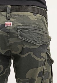 Spodnie cargo w odcieniach zieleni z wieloma kieszeniami, czarnym plecionym paskiem i metką G-Star Originals z tyłu. Materiał z fakturą.