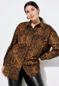 Leopardmønstret skjorte i brun og sort, knaplukning, lange ærmer, to brystlommer, lavet af blødt stof, afslappet pasform.