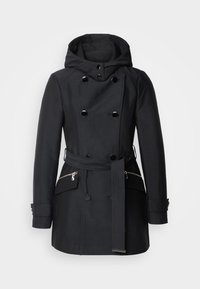 Manteau noir avec capuche, design croisé, grands boutons, ceinture amovible et poches latérales zippées. Texture de tissu lisse.