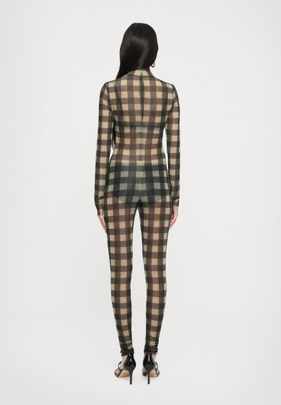 Form-fitting bodysuit in a brown, beige, and black plaid pattern. Long sleeves, high collar, and tapered legs. Worn with black heels.