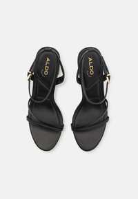 Sandale negre cu bretele subțiri, design elegant, stil cu vârf deschis și cataramă ajustabilă la gleznă; branț texturat cu logo embossat.