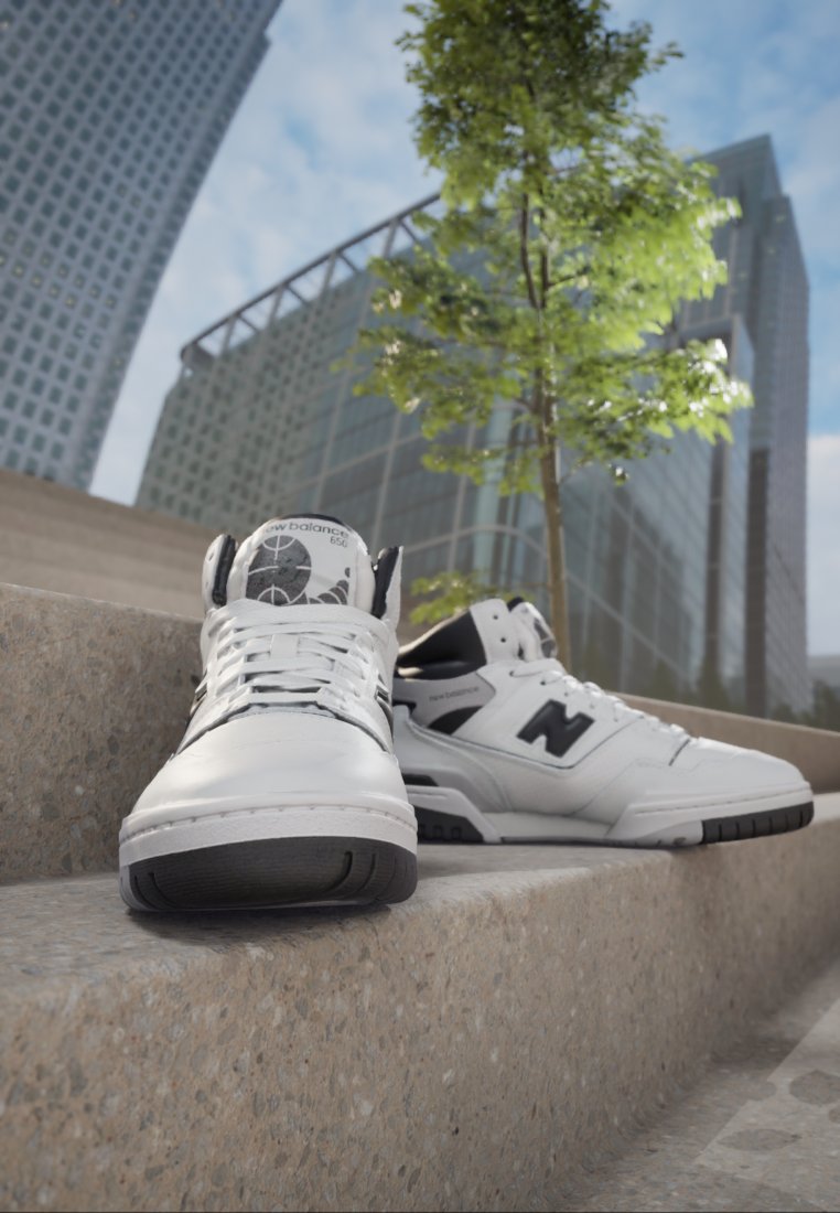 Baskets New Balance blanches avec des accents noirs, présentant un design montante, une tige en cuir lisse et une semelle en caoutchouc texturé. Logo et branding visibles.