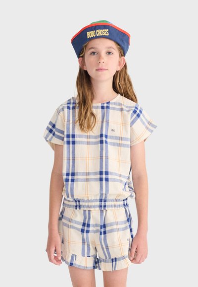 Fille portant une tenue deux pièces à carreaux bleu, orange et blanc avec un short à volants et un chapeau bleu marine avec le texte "BOBO CHOSES".