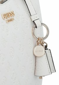 Sac à main synthétique blanc texturé avec logo embossé, ferrures dorées, porte-clés rond et petite étiquette. Présente des coutures d'accent noires.