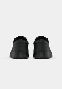 Czarne buty sportowe o gładkiej teksturze, zaokrąglonym obcasie i amortyzującym wsparciu. Charakteryzują się minimalnym brandingiem po boku oraz trwałym wzorem podeszwy.