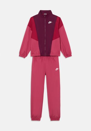 Nike trainingspak in tinten van roze en bordeauxrood, met een ritsjack met lange mouwen en bijpassende elastische broeken. Opvallende logo-accenten.