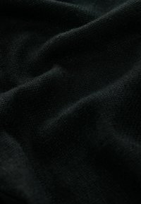 Tissu noir doux avec un motif légèrement texturé et des plis doux créant des variations subtiles d'ombre.