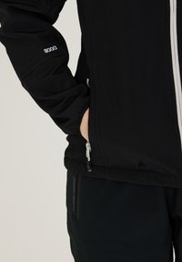 Černá softshellová bunda s brandingem W-PRO 8000, s předním zipem a bočními kapsami, spárovaná s tmavými kalhotami s označením W-PRO 1500.