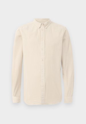 Camicia beige a maniche lunghe realizzata in tessuto morbido. Presenta una chiusura frontale con bottoni, colletto a punta e polsini abbottonati, con una sottile texture.