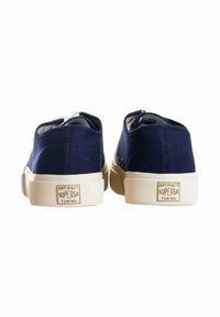 Sneakers in tela blu con suola in gomma beige, caratterizzati da una finitura testurizzata e dettaglio del logo sul tallone. Design classico a basso profilo.